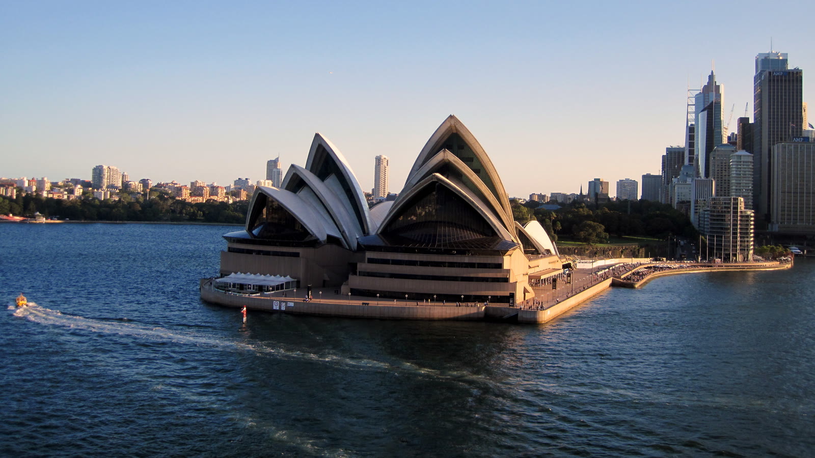 Operahuset i Sydney set fra havnen med byens højhuse i baggrunden