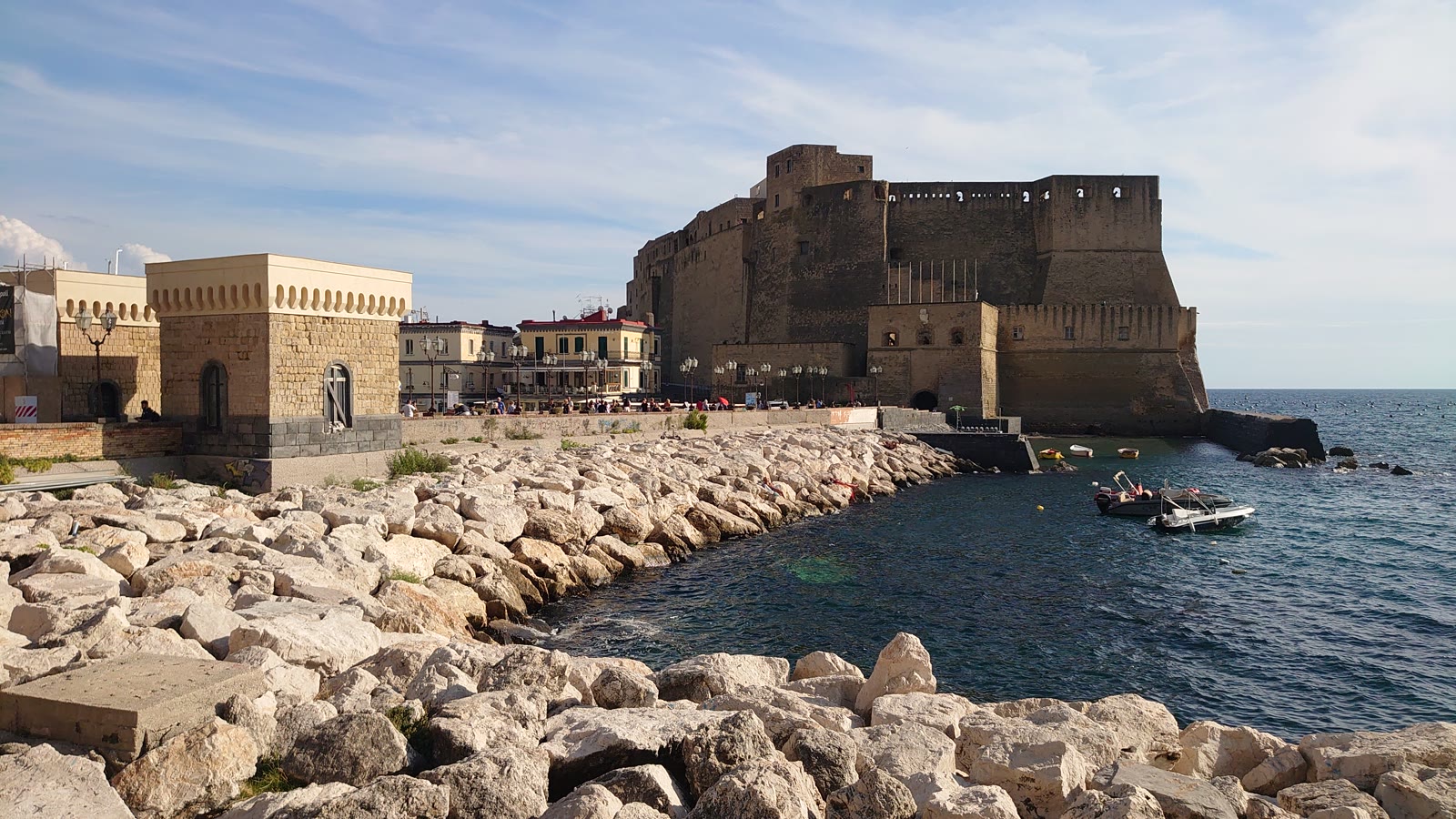 Castel dell'Ovo på klippeøen Megaride i Napoli set fra stenmolen, med restauranterne i Borgo Marinari og havet omkring