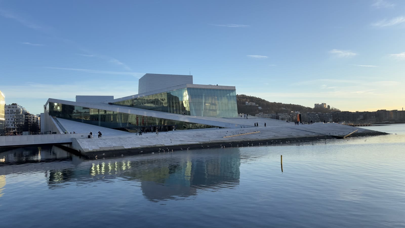 Operahuset i Oslo set fra fjorden med det skrånende marmortag og Ekebergåsen bagved