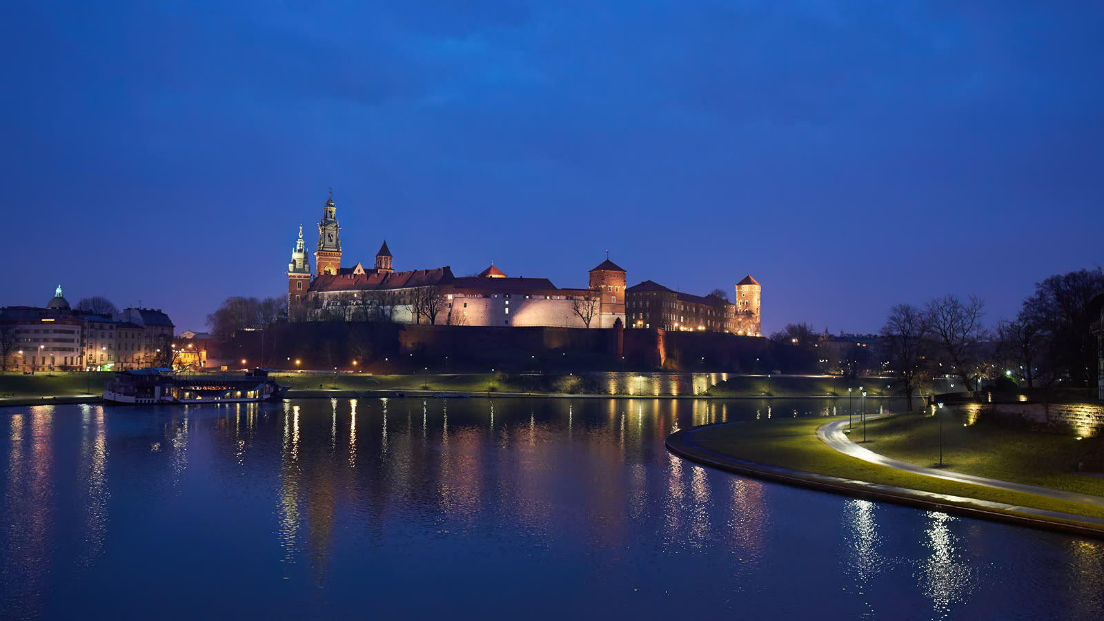 Wawel-slottet og katedralen i Kraków oplyst i blå time, spejlet i floden Wisła
